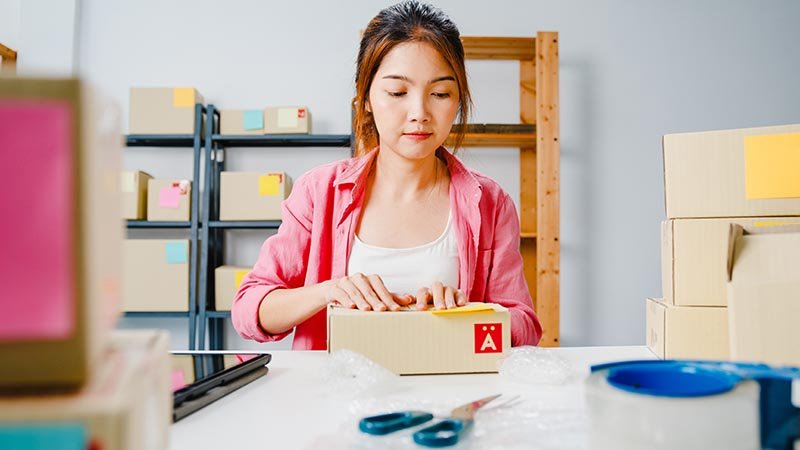 young asia entrepreneur businesswoman packing product in cardboa